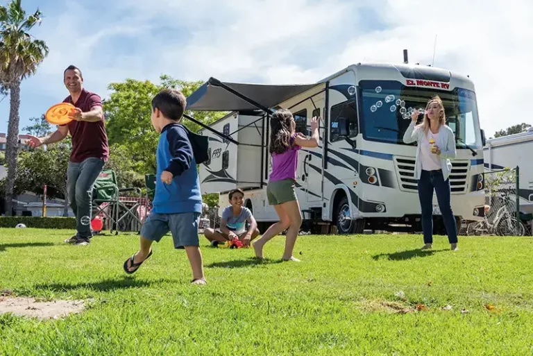 family playing frisbee in front of RV