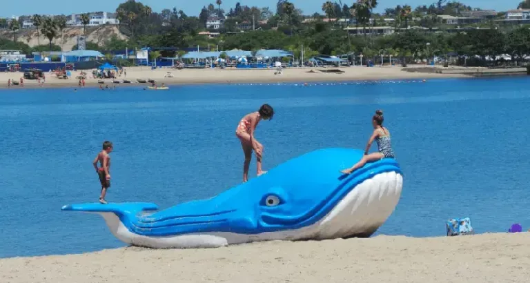 kids playing on Moe the Whale on the beach
